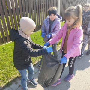 Uczniowie klasy 1 zbierają śmieci wzdłuż drogi do lasu